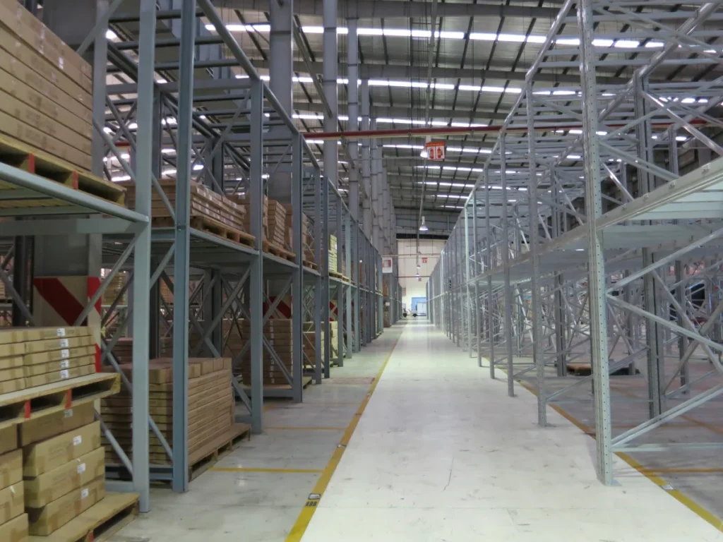 Nền bê tông phẳng có vạch sơn phân lối đi giữa các dãy kệ pallet cao