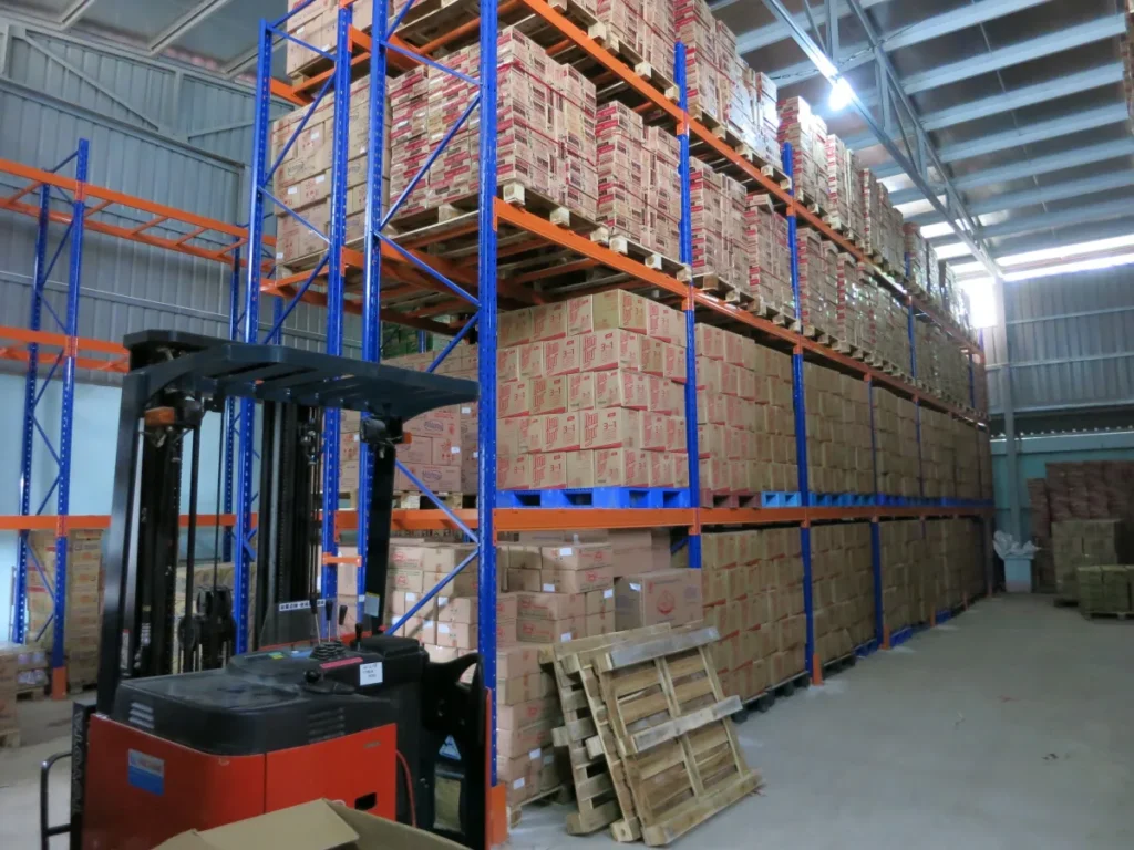 Xe nâng reach truck lấy pallet hàng thùng từ kệ Selective trong lối đi